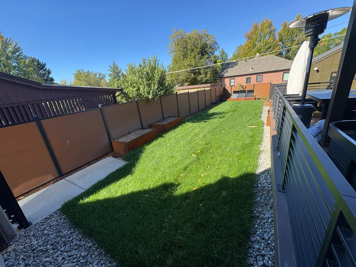 Backyard with a lawn and empty raised beds along a fence